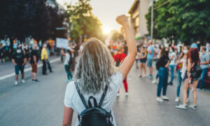 Young Woman With A Raised Fist Protesting In The Street