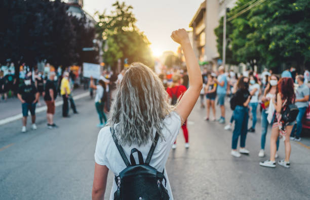 Young Woman With A Raised Fist Protesting In The Street